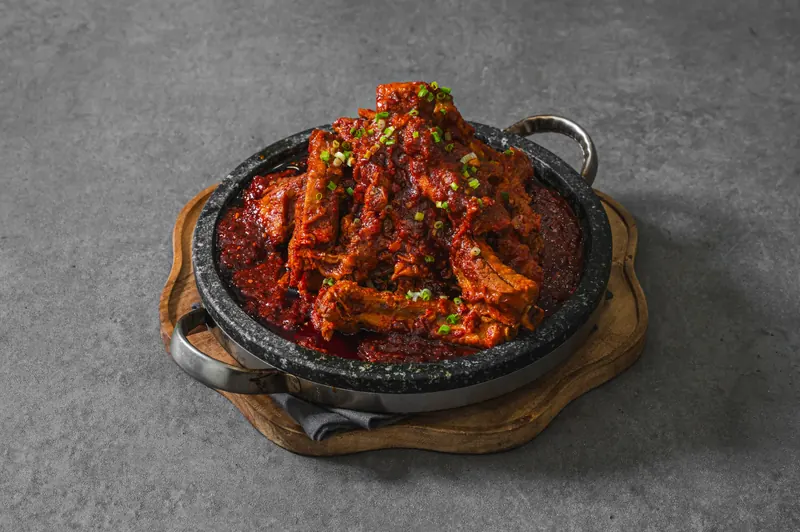 돌판에 봉긋하게 쌓아 올린 양념 등갈비구이를 비스듬히 본 모습