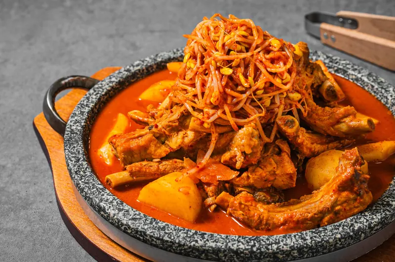 콩나물이 올라간 얼큰한 돌판 김치 등갈비찜과 감자 클로즈업